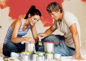 Young couple testing out paint colors on home walls.