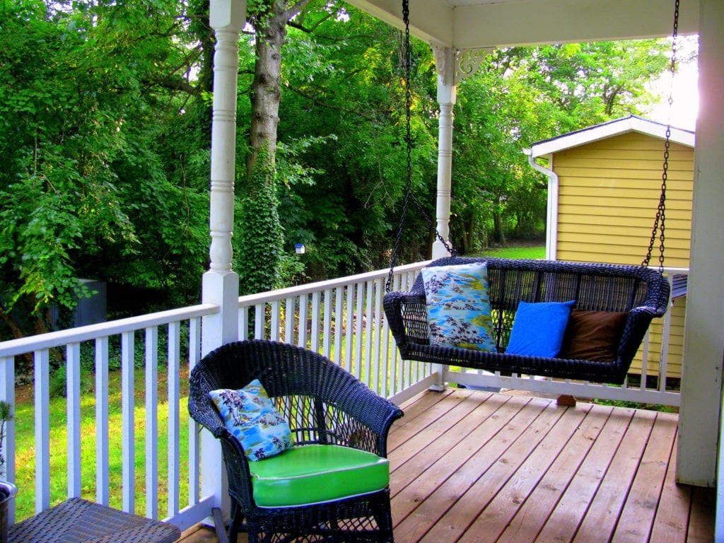 Porch of custom home with swing and chair.
