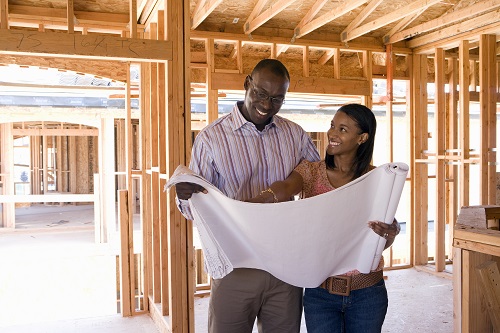 Young Couple Looking At House Plans in Their House Under Construction - Local House Builders Blog
